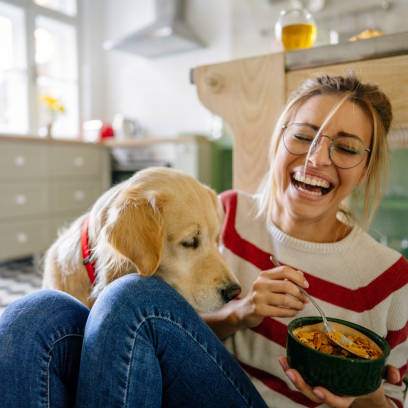 Photo of young woman and her dog in a kitchen at the morning